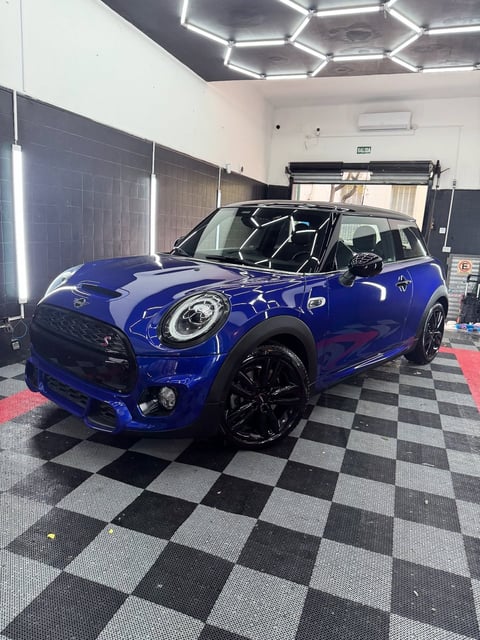 Mini Cooper azul con techo abierto en exhibición